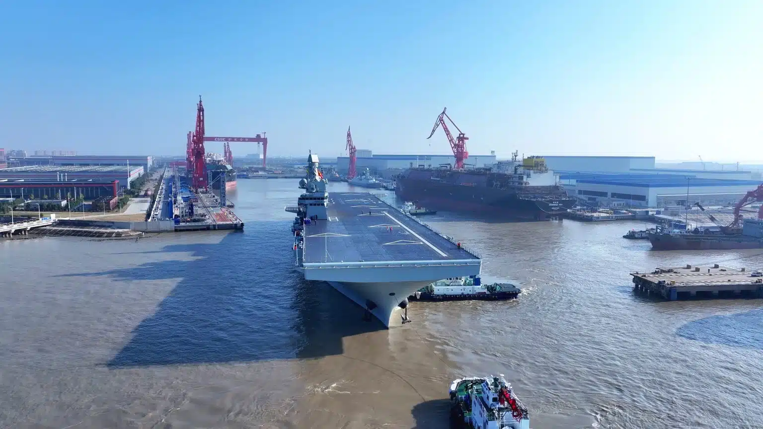 Το Σετσουάν εγκαταλείπει τη λεκάνη εγκατάστασης στο Χουντόνγκ στο νησί Τσανγκσίνγκ. Σημειώστε τη φρεγάτα τύπου 054AG PLAN στο βάθος. Η εταιρεία κατασκευής Jiangnan της Φουτζιάν έχει τις δικές της εγκαταστάσεις στα αριστερά αυτής της εικόνας. Φωτογραφία από τα κρατικά μέσα ενημέρωσης της Κίνας.