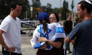 Άνθρωποι αγκαλιάζονται καθώς επισκέπτονται τον τόπο των πυροβολισμών σε μια εβραϊκή γιορτή στην παραλία Μπόντι