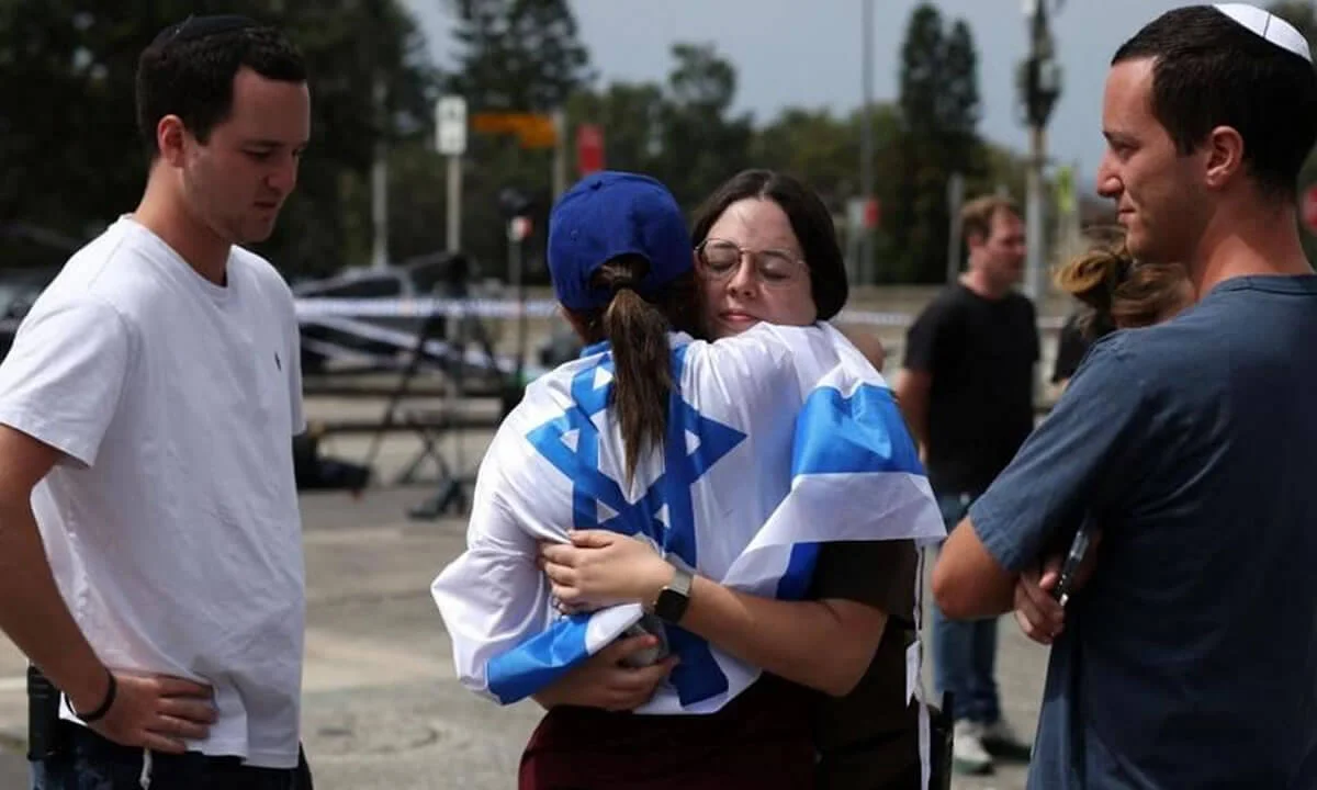 Άνθρωποι αγκαλιάζονται καθώς επισκέπτονται τον τόπο των πυροβολισμών σε μια εβραϊκή γιορτή στην παραλία Μπόντι